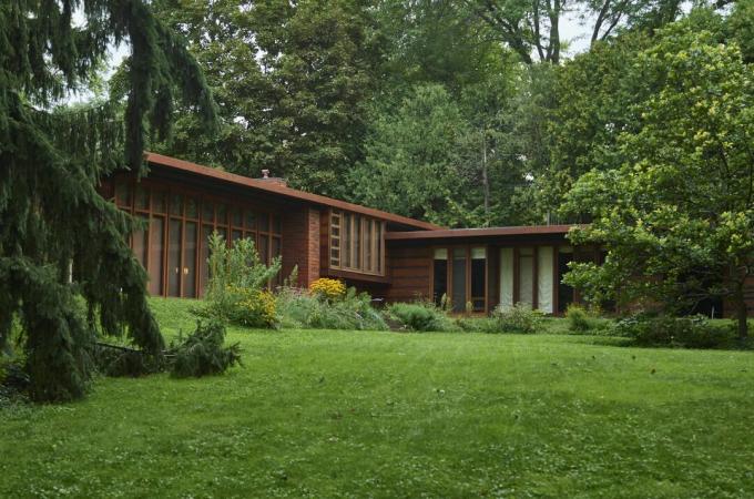 Pequeña casa moderna horizontal de rancho de vidrio vertical y madera en un entorno de madera