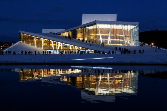 Vista nocturna de la Ópera de Oslo iluminada en Noruega