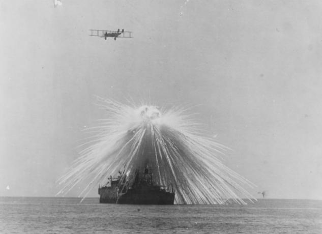 Una nave es alcanzada por una bomba mientras un avión vuela.