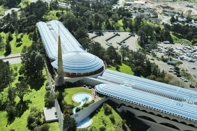 Vista aérea de un extenso edificio alado a ambos lados de una cúpula redonda, baja, horizontal, orgánica a la tierra