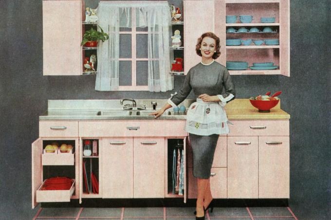 Ilustración vintage de una ama de casa de moda de pie delante de su nueva cocina rosa, 1957