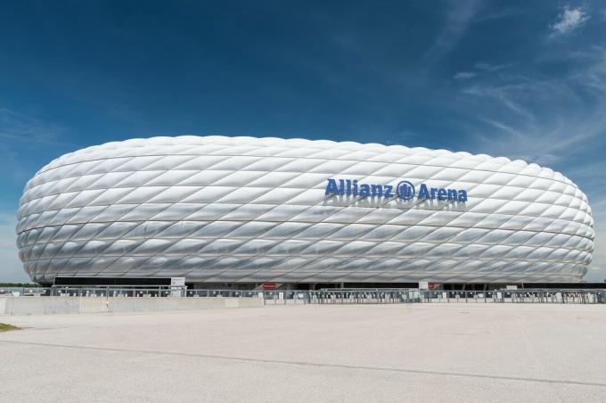 Vista lateral del estadio deportivo curvo, exterior esculpido de paneles de plástico inflados de ETFE, con el aspecto de un neumático blanco cosido en su costado