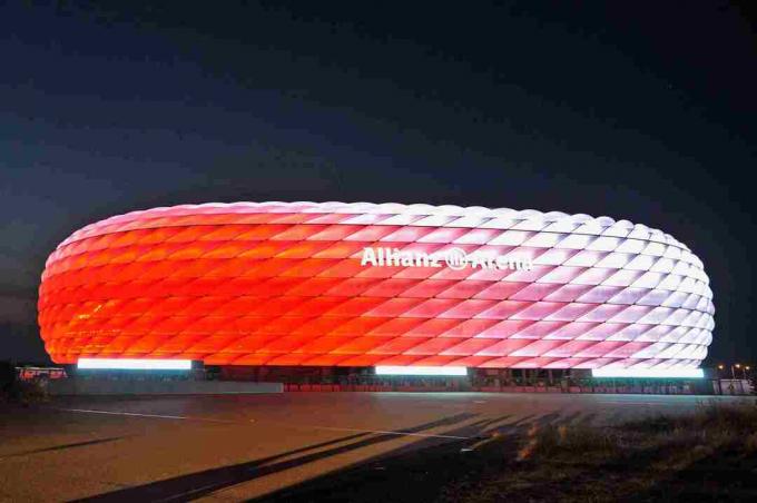 blanco de día, el exterior esculpido de Allianz Arena se ilumina de rojo por la noche