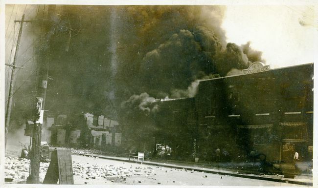Propiedades dañadas y humo proveniente de edificios luego de la Masacre de Tulsa Race, Tulsa, Oklahoma, junio de 1921.