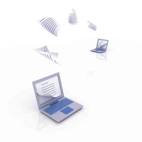 Papel flotando de una computadora portátil a otra, que muestra la transferencia de archivos de blog de WordPress a Blogger