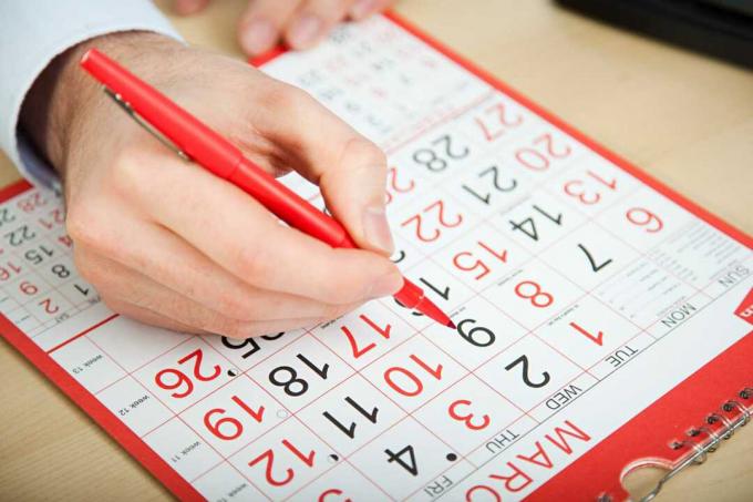 Mano elegiendo fecha sobre calendario.