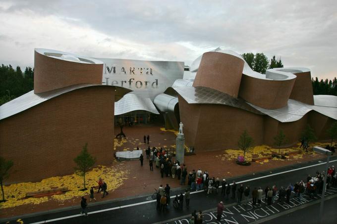 Visión a largo plazo del techo ondulado de metal en un edificio de ladrillo rojo llamado MARTa Herford - La gente hace cola para ingresar al museo 'MARTa' el 7 de mayo de 2005 en Herford, Alemania. El museo de arte y diseño contemporáneo, diseñado por el arquitecto estrella estadounidense Frank Gehry, ofrece un espacio de exposición de 2.500 metros cuadrados y se completó después de un tiempo de construcción de cuatro años.