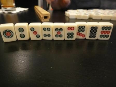 El traje de piedras de un conjunto estándar de fichas de Mahjong de pie sobre una mesa.