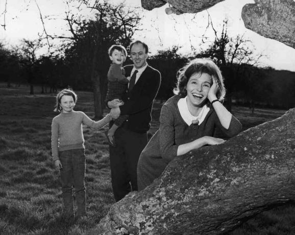 Foto en blanco y negro de Roald Dahl con sus hijos; su esposa Patricia Neal se apoya en un árbol