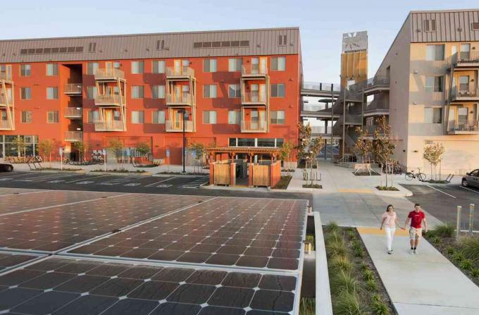 Dos personas caminando cerca de edificios ecológicos y paneles solares, en una comunidad de energía neta cero