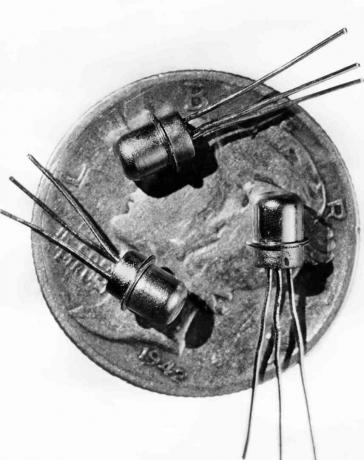 Imagen de 1956 de tres transistores M-1 en miniatura que se ven en la cara de una moneda de diez centavos