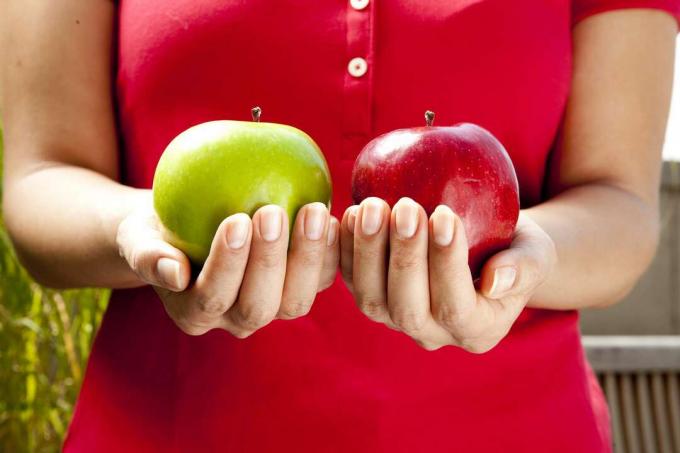 persona con manzanas verdes y rojas