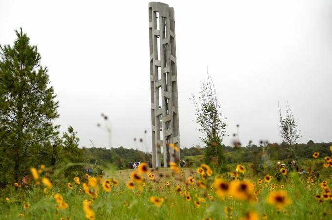 alto y delgado campanario de piedra en un campo de flores